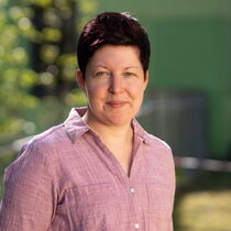 Portraitfoto Julia Ladislau - Sie trägt kurzes dunkles Haar und ein hellrosa Hemd.