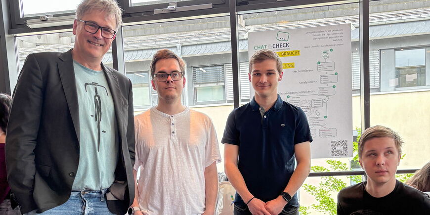 Otfrid Altfeld steht mit den drei Preisträgern im Cineplex vor einem Plakat, das über ihr Projekt informiert.