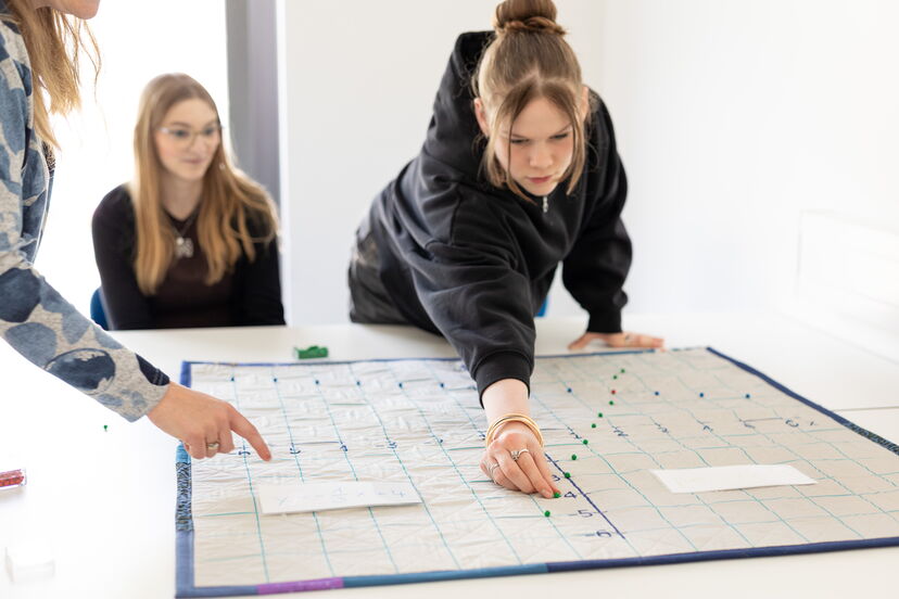 Eine Schülerin Steckt Nadeln in ein Koordinatensystem aus Stoff.