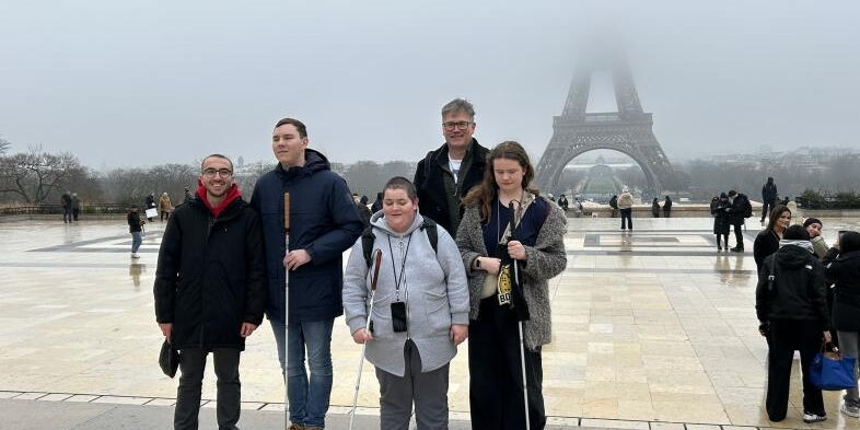 Vier Schüler*innen stehen mit Otfrid Altfeld auf einem Plateau, im Hintergrund ist der in Nebel eingehüllte Eiffelturm zu erkennen.