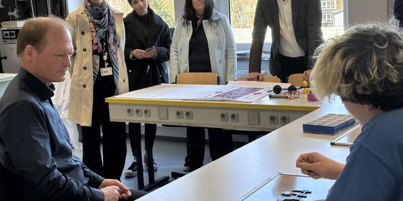 Die Gäste schauen sich an, wie ein Schüler ein Multimediales Lernpaket Chemie nutzt.