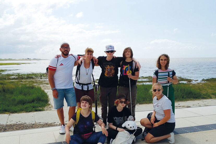 Gruppenfoto der WG am Weinberg an einer Promenade, im Hintergrund die Nordsee