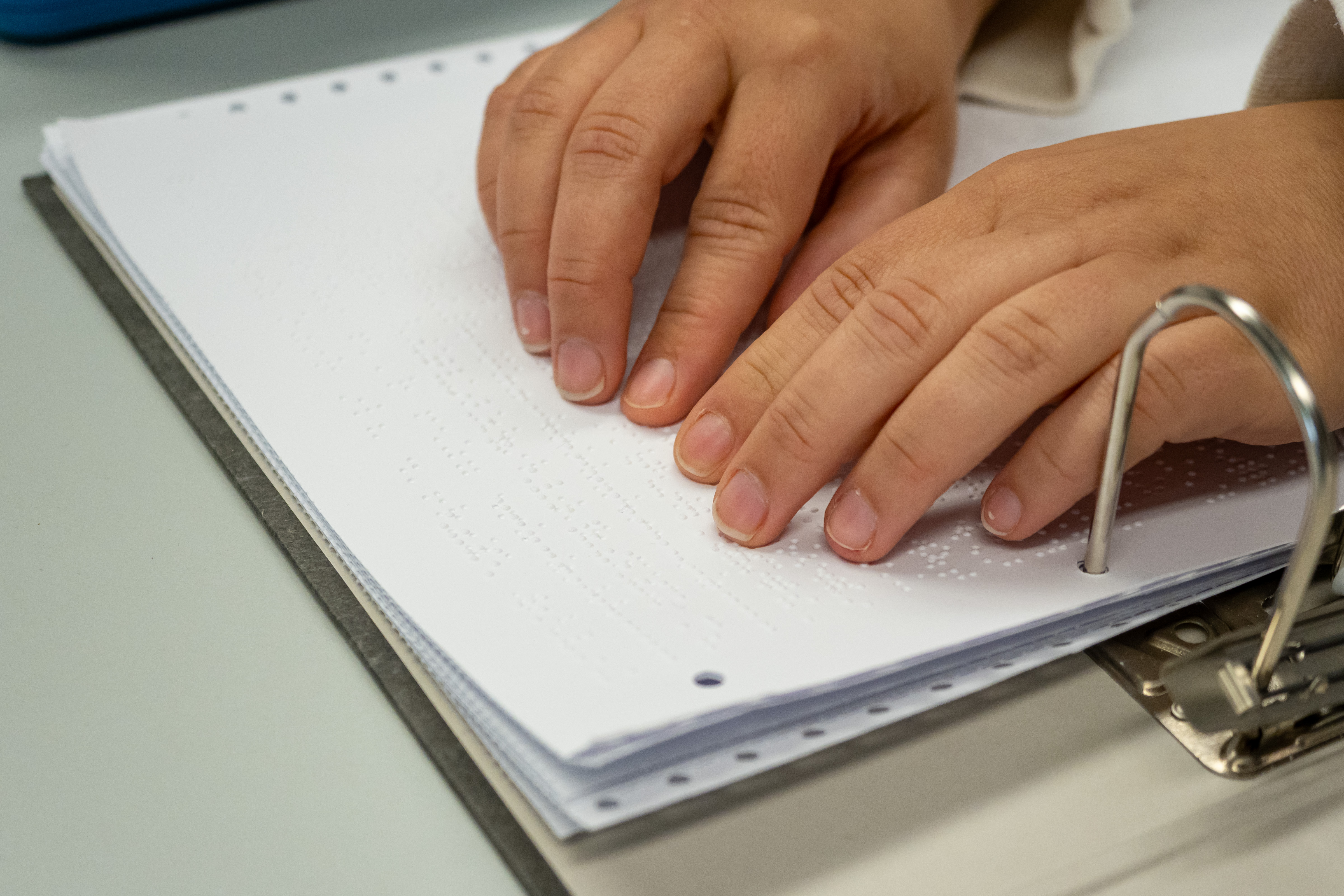 Zwei Hände lesen mit den Fingern Braille.